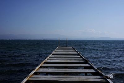 Pier over sea against blue sky