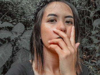 Portrait of beautiful young woman against plant