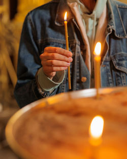 Midsection of man lighting candles