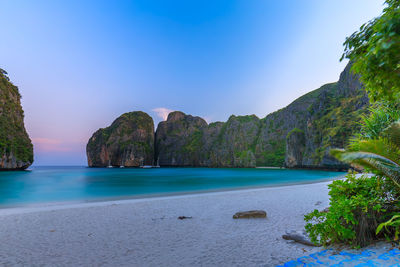 Scenic view of sea and mountains against clear blue sky