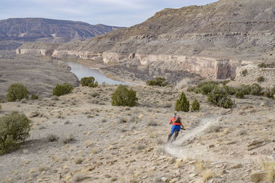 Rear view of man walking on mountain against sky