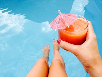 Low section of woman relaxing by swimming pool