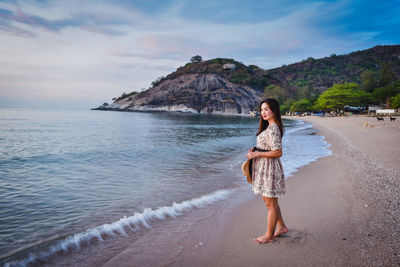 Full length of woman standing on beach against sky