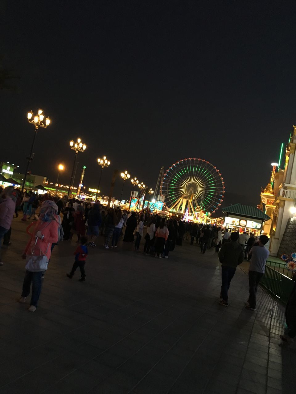 illuminated, night, large group of people, arts culture and entertainment, leisure activity, lifestyles, celebration, lighting equipment, enjoyment, mixed age range, crowd, fun, event, city, cultures, amusement park ride, sky, tourism, city life, outdoors, decoration, travel destinations