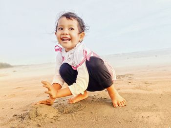 Portrait of boy sitting at sandy beach