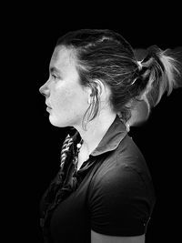 Portrait of woman looking away against black background