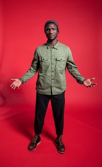 Portrait of young man standing against red background