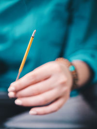 Midsection of woman holding burning incense