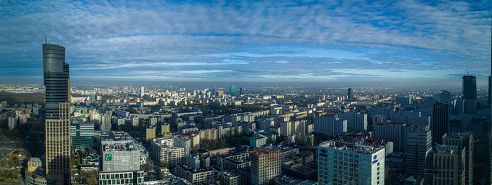 Aerial view of city buildings against cloudy sky