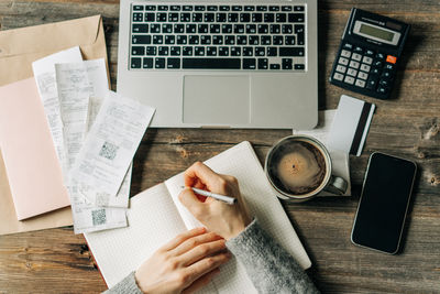 Top view of the workplace of an accountant writing in a notebook.