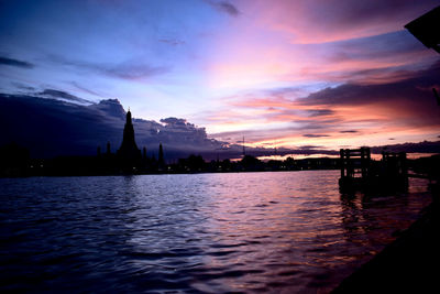 Silhouette of city at waterfront during sunset