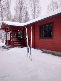 Snow covered house by building on field during winter