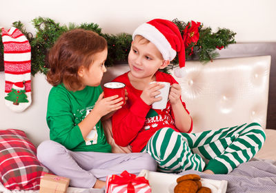 Portrait of siblings sitting on sofa at home