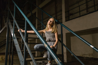 Young woman crouching on steps in factory