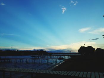 Silhouette bridge over lake against sky during sunset