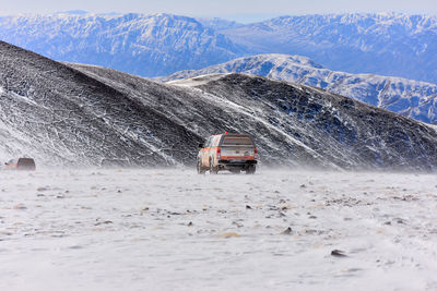 Car on snow covered field by mountains