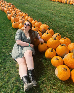 Full length of woman sitting by pumpkins