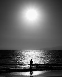 Silhouette woman on beach against sky