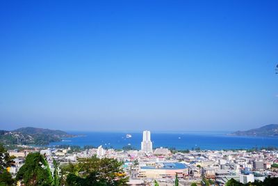 Buildings by sea against blue sky