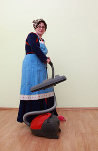 Full length of woman cleaning house with vacuum cleaner