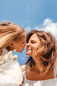 Close-up of daughter kissing mother against sky