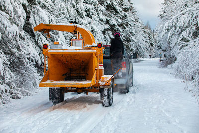 Snow covered road amidst trees during winter