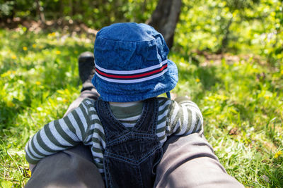 Midsection of man wearing hat sitting on field