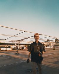 Portrait of smiling young man standing on bridge against sky