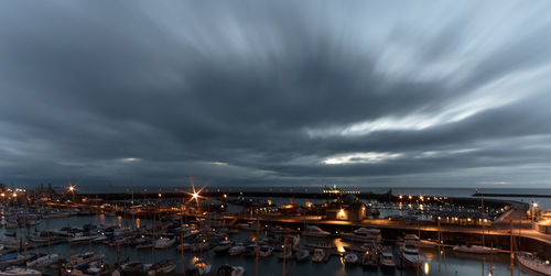 Boats moored at harbor against cloudy sky during dusk