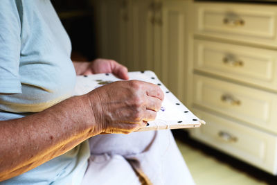 Midsection of senior women hands doing needle work in the kitchen of her home