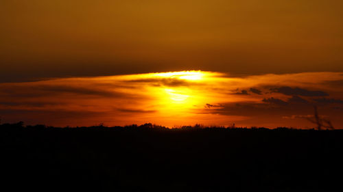 Scenic view of silhouette landscape against orange sky