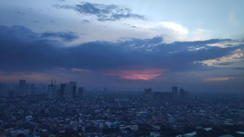 Aerial view of buildings in city against sky during sunset