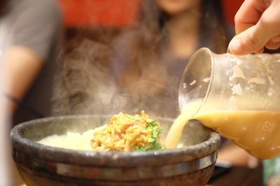 Cropped hand pouring liquid in food