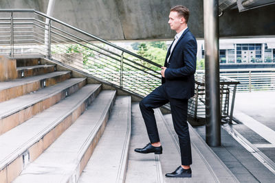 Full length of young businessman walking on staircase