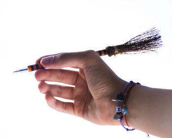 Close-up of hand holding cigarette against white background