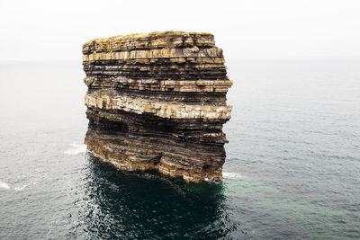 Rock formation in sea against sky