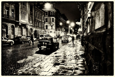Cars on city street amidst buildings at night