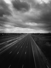 Road passing through landscape against cloudy sky