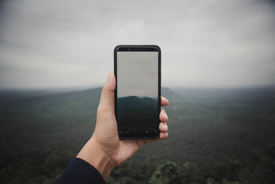 Hand of person photographing landscape from smart phone