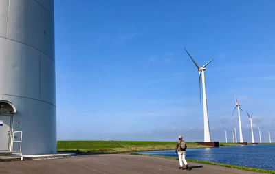 Rear view of man on windmills against blue sky