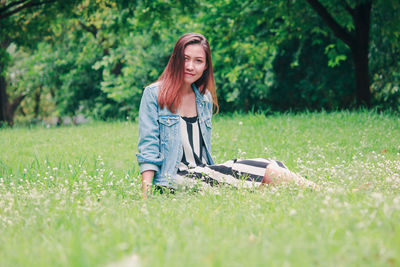 Full length portrait of young woman on grass