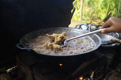 Midsection of person preparing food in cooking pan