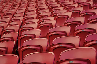 Empty red plastic seats in an empty stadium. many empty seats for spectators in the stands.