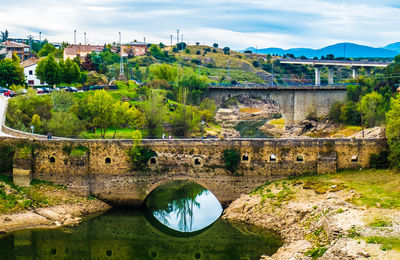 Arch bridge over river against sky