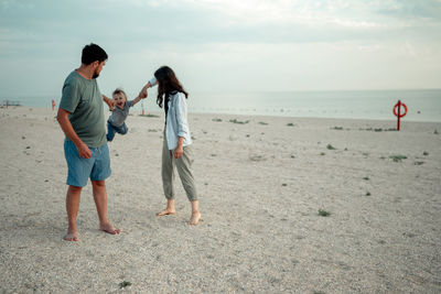 Rear view of man standing at beach against sky