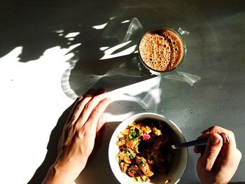 High angle view of woman holding coffee cup on table