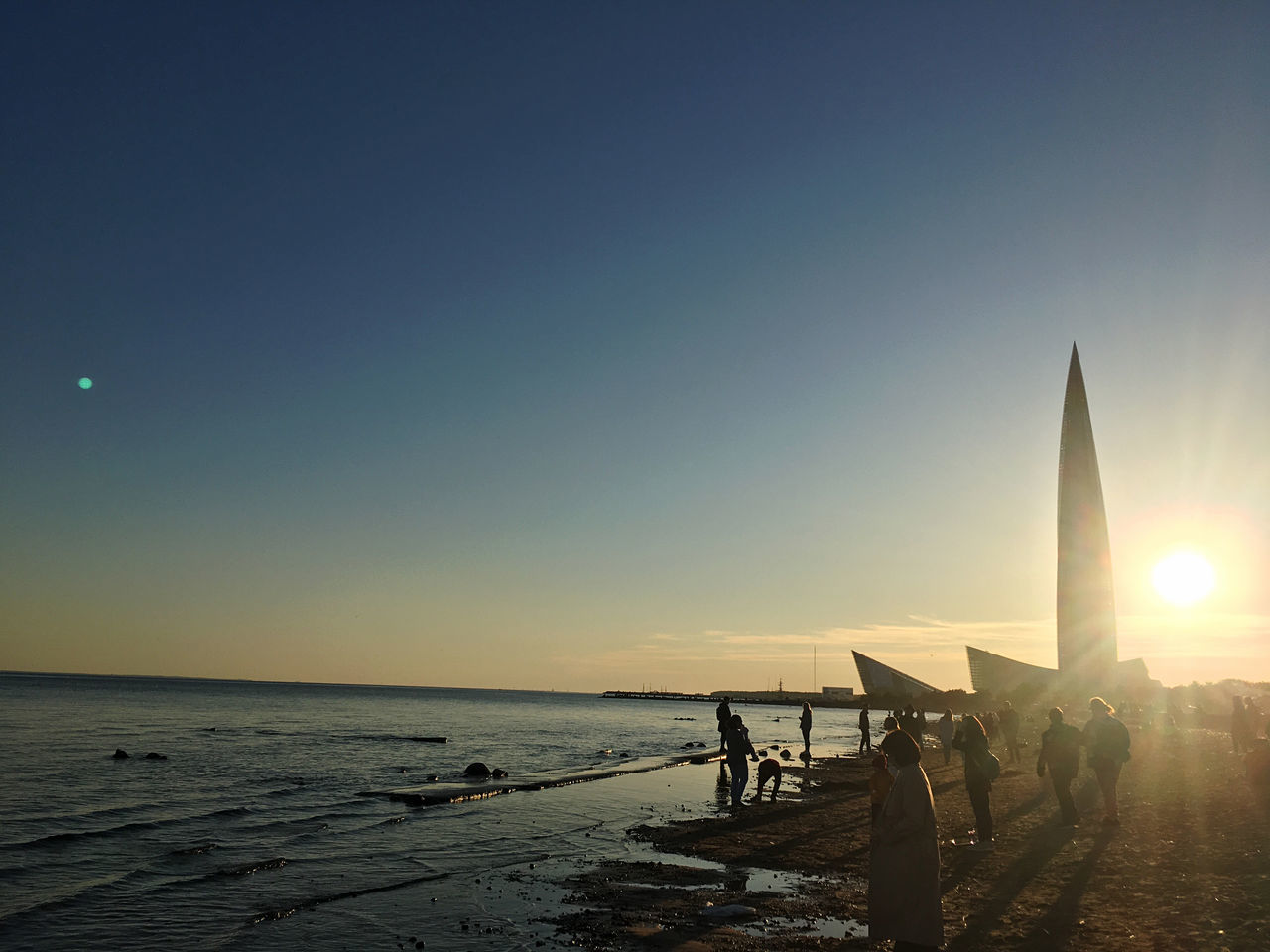 PEOPLE ON BEACH AGAINST CLEAR SKY AT SUNSET