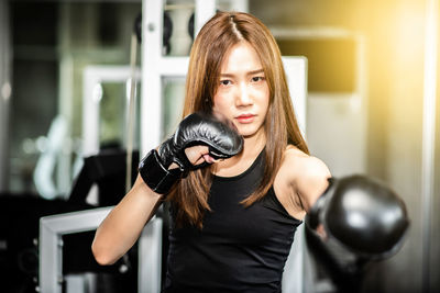 Portrait of confident young woman practicing boxing in gym
