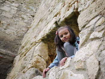 Girl looking away while standing on rock