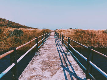 Footbridge over landscape against clear sky